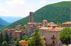 una pequeña ciudad en una colina con una montaña en La Casa del Ciarlatano, en Cerreto di Spoleto