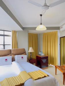 Schlafzimmer mit einem großen weißen Bett und gelben Vorhängen in der Unterkunft LEYSHOF HOTEL in Mwanza