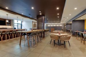 a restaurant with tables and chairs and a bar at Holiday Inn Mobile Airport by IHG in Mobile