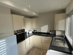 a kitchen with white cabinets and a black counter top at St Martins Holiday Home Contractors Welcome in Thorngumbald