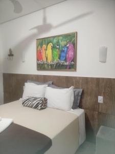 1 dormitorio con 1 cama con una pintura en la pared en Pousada da Gi Suítes e Turismo, en Chapada dos Guimarães