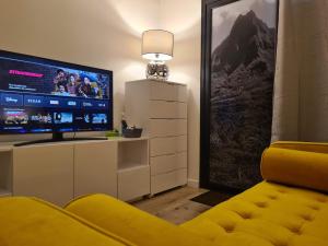 sala de estar con sofá amarillo y TV de pantalla plana en Studio Ninirei en Papeete