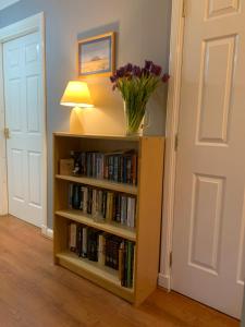 un estante de libros con un jarrón de flores. en Brada View Bamburgh, en Bamburgh