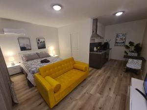 a yellow couch in a bedroom with a bed at Studio Ninirei in Papeete