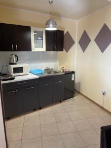 a kitchen with black cabinets and a microwave at Diva Apartments & Diva restaurant BBQ&pool bar in Varna City