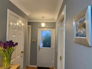 a hallway with a white door and a vase of purple flowers at Brada View Bamburgh in Bamburgh