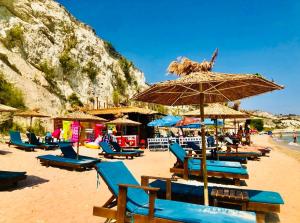 a beach with blue chairs and an umbrella at Royal Apartment Sea view by Kaliakria in Topola