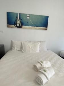 a white bed with towels on it with a guitar at Central Motel Mudgee in Mudgee