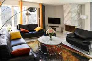 sala de estar con mesa y muebles de cuero negro en Villa pré d'Oro - 1000 étangs en Amage