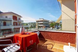 une table rouge sur un balcon avec vue sur une rue dans l'établissement Casa vacanze Gigli, à Numana