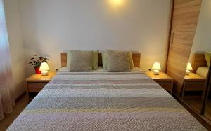 a bedroom with a large bed with two lamps at Holiday apartman in Kaštela