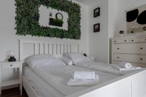 a white bedroom with a white bed with ivy on the wall at Zemplén Gyöngye Vendégház in Erdőhorváti +42 photos