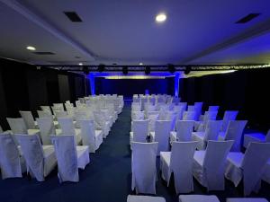 una habitación con sillas blancas y un escenario con luces azules en Business Hotel Prijedor, en Prijedor