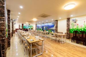 a restaurant with tables and chairs in a room at Victor Charlie Hostel in Cat Ba