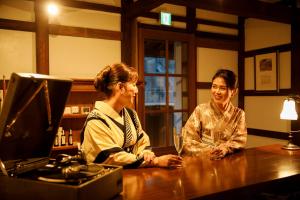 Zwei Frauen sitzen in einer Bar mit einem Computer in der Unterkunft Machi no Odoriba in Kanazawa