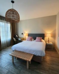 a bedroom with a large white bed and a bench at Hôtel Marguerite in Orléans
