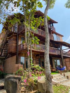 een houten huis met bomen en bloemen ervoor bij Green Bamboo Lodge Resort in Cat Tien