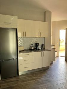 a kitchen with white cabinets and a stainless steel refrigerator at Cozy apartment Costa Adeje in Adeje