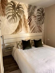 a bedroom with a white bed with plants on the wall at Cozy apartment Costa Adeje in Adeje