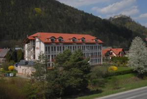 un edificio con techo rojo frente a una montaña en Hotel Podhradie, en Považská Bystrica