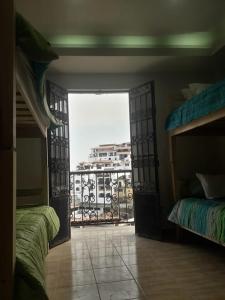 an open door to a room with two beds and a balcony at Hostal Casa Pajaritos in Taxco de Alarcón