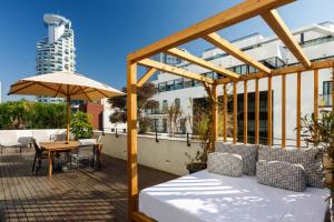 um pátio com uma cama, um guarda-chuva e uma mesa em Renoma Apartments em Tel Aviv