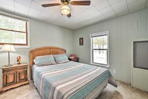 1 dormitorio con 1 cama y ventilador de techo en Rose City Cabin with Fire Pit and Lake Access, 
