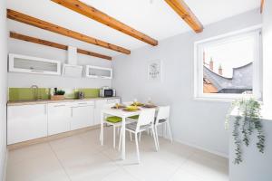 グダニスクにあるArtus apartmentsの白いキャビネット、テーブルと椅子付きのキッチンが備わります。