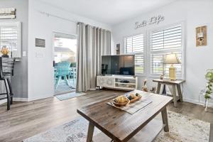 a living room with a table and a tv at Hook, Wine, & Linger condo in Destin