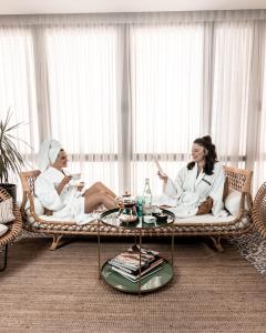 two women sitting on a couch in a room at Renoma Apartments in Tel Aviv