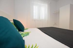 Cama blanca con almohadas verdes y ventana en Lavanda, en Mandre