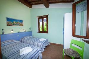 a hotel room with two beds and a chair at Villa Aiali in Marina di Campo