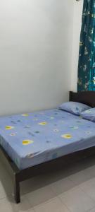 ein Bett mit blauer Bettdecke und gelben Etiketten darauf in der Unterkunft Kerian Putra Muslimstay in Parit Buntar