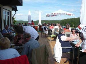 eine Gruppe von Personen, die auf einer Terrasse an Tischen sitzen in der Unterkunft Löwen Patisserie in Schönwald