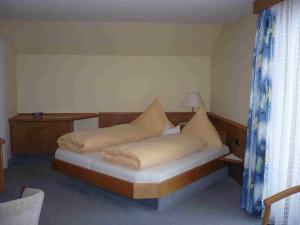 ein kleines Schlafzimmer mit einem Bett mit Kissen darauf in der Unterkunft Löwen Patisserie in Schönwald