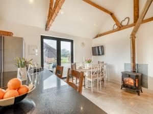 a kitchen and dining room with a table and a wood stove at Archies Barn in Lenwade