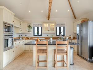 a kitchen with a island with two chairs and a refrigerator at Archies Barn in Lenwade