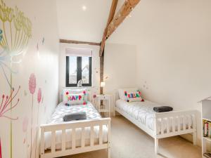 a room with two white beds and a mirror at Archies Barn in Lenwade