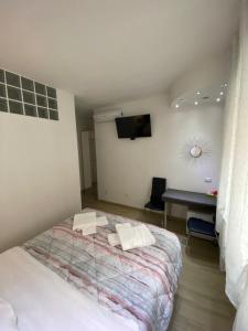 Schlafzimmer mit einem Bett, einem Schreibtisch und einem TV in der Unterkunft Vapama Rooms in Verona