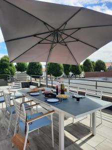 une table blanche avec des chaises et un parasol dans l'établissement Appartement au Crotoy, au Crotoy