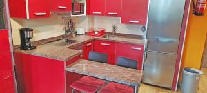 La cuisine est équipée de placards rouges et d'un réfrigérateur en acier inoxydable. dans l'établissement Apartamento Piscina y Playa, à San Juan de la Arena