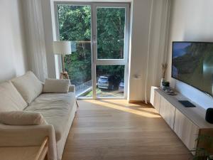 a living room with a couch and a flat screen tv at Sunny apartment with forest view in Juodkrantė