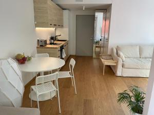 a kitchen and a living room with a table and chairs at Sunny apartment with forest view in Juodkrantė