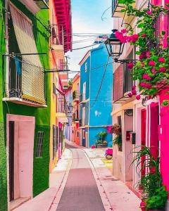 a narrow street with colorful buildings and flowers at Ksar azul 6 pers à 2 mn de la plage in Villajoyosa