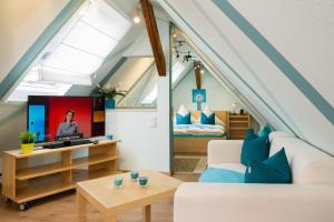 ein Wohnzimmer mit einem Sofa und einem TV im Dachgeschoss in der Unterkunft Ferienwohnungen Am Markt in Rüdesheim am Rhein