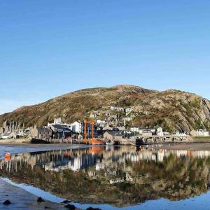 a reflection of a town in a body of water at Harbourside 2 Bed apartment, Barmouth Bridge Views in Barmouth