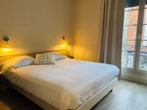 een slaapkamer met een groot wit bed met 2 kussens bij Hôtel Marguerite in Orléans