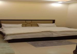 1 dormitorio con 1 cama grande con sábanas y almohadas blancas en Mayur Palace By WB Inn en Agra