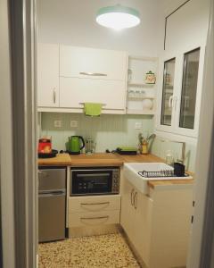 a kitchen with white cabinets and a stove top oven at MimaDart Pop-up Gallery Apartment in Piraeus