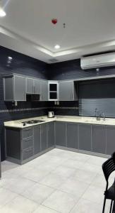 une grande cuisine avec des placards gris et un évier dans l'établissement الجناح الأبيض للأجنحه الفندقية, à Dammam